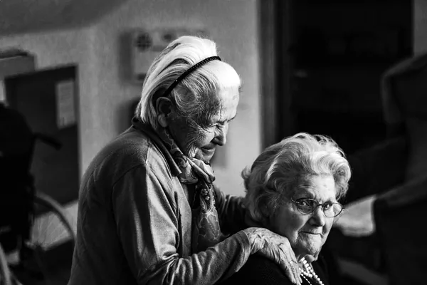 Two older women sharing a quiet moment together, in black and white