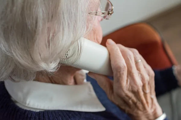 An older woman at home holding a cup with both hands