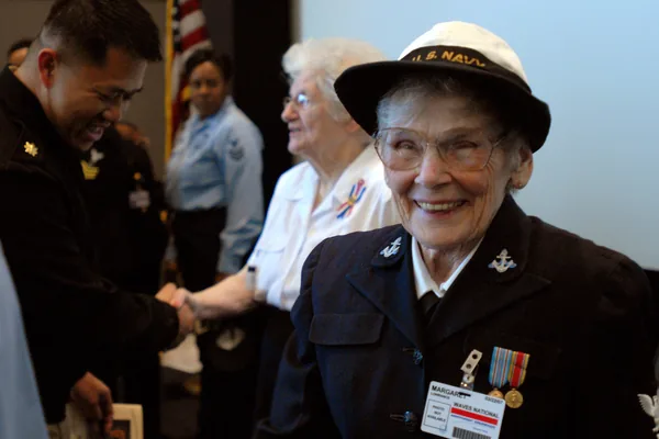 A smiling World War II Navy veteran wearing her cap and service medals