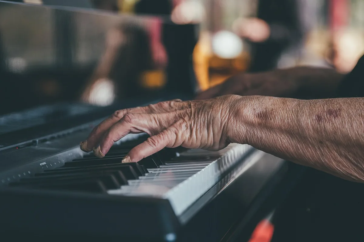 Close-up of an older person's hands playing the keys of a piano