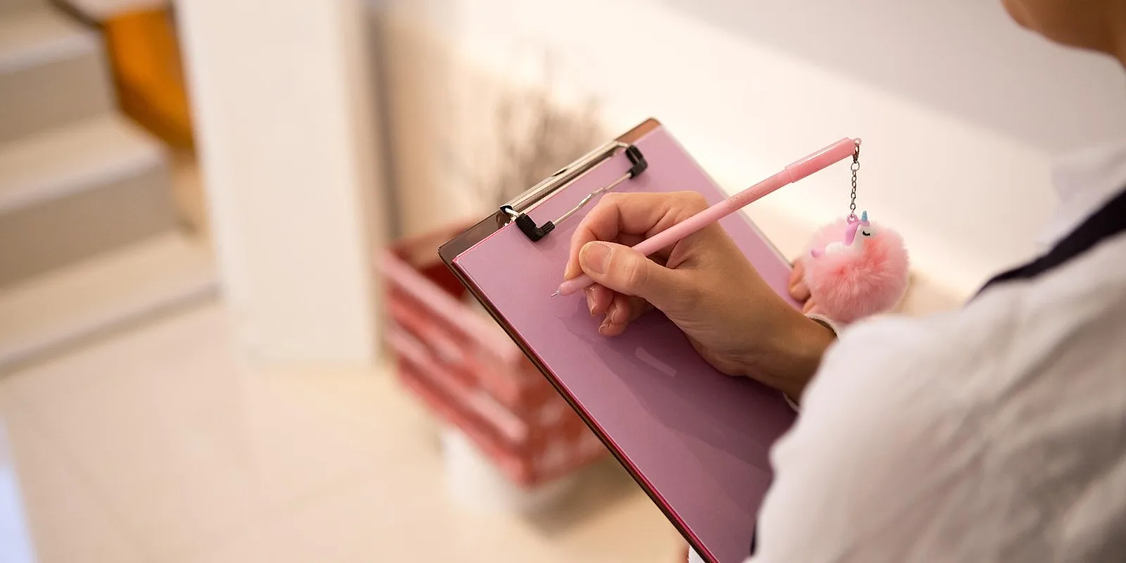 A hand writing notes on a clipboard with a pen